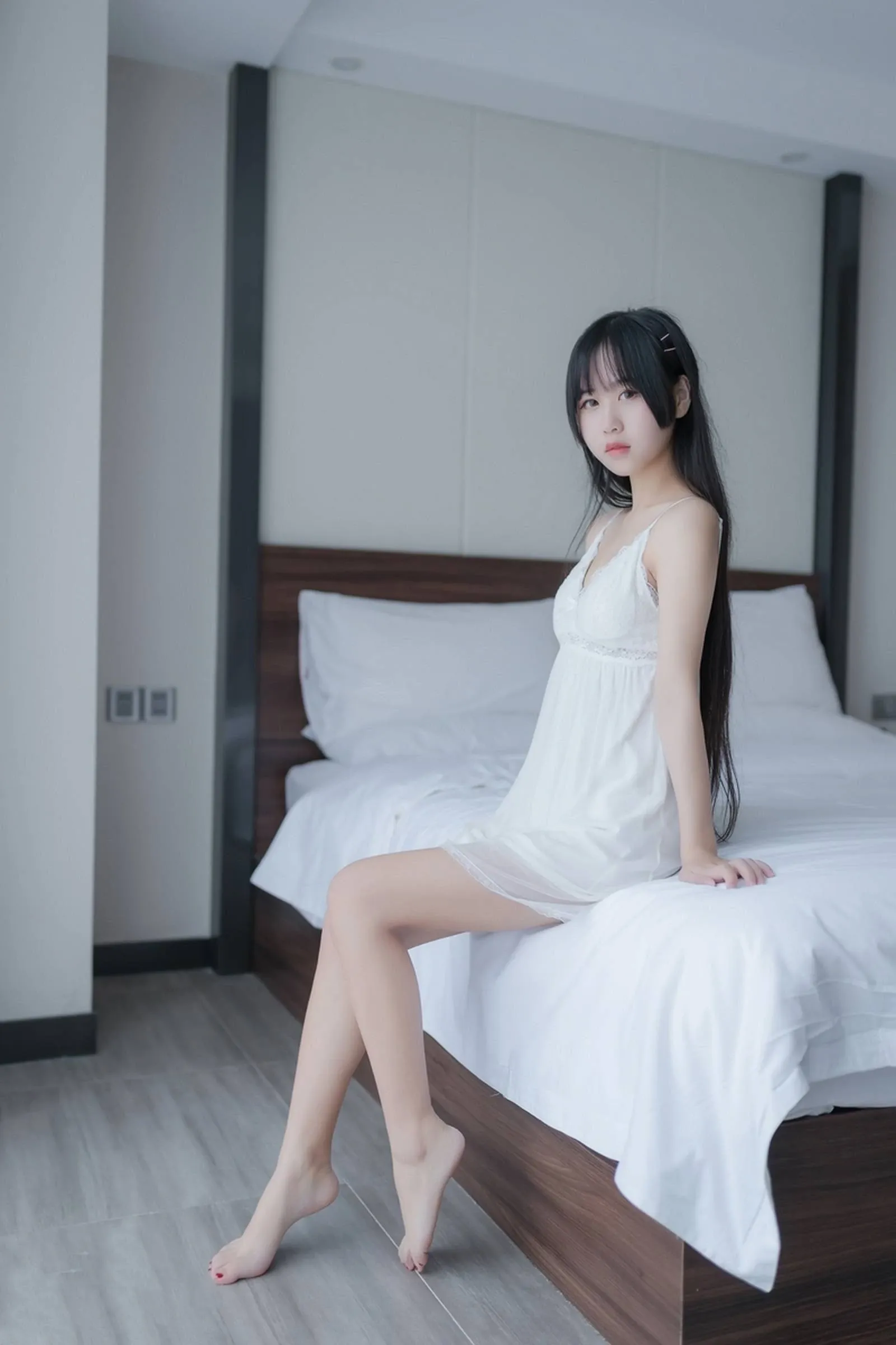 萌芽儿o0身穿白色吊带睡裙坐在床边